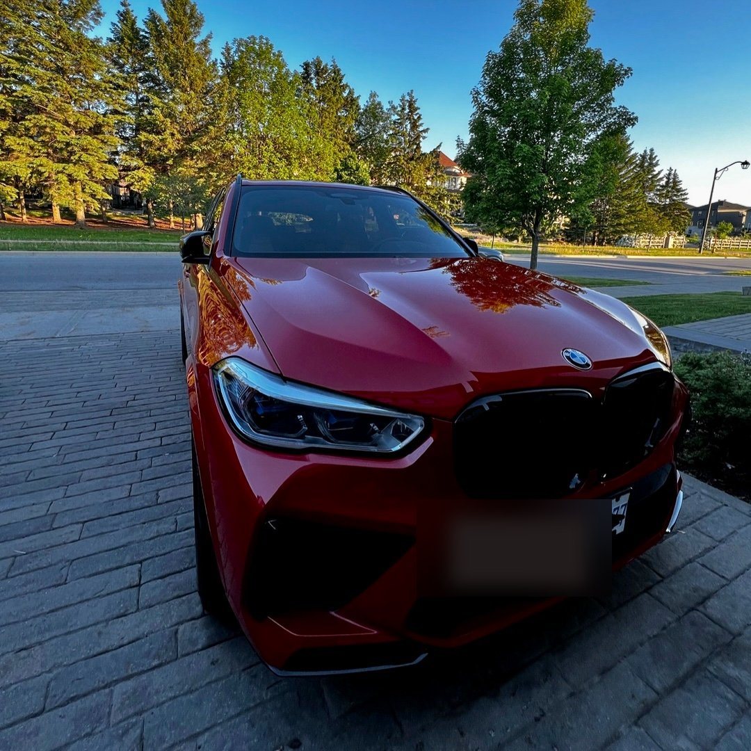 Finished detail — BMW X5 M Competition in red at golden hour, mirror-finish paint, clean grille and wheels